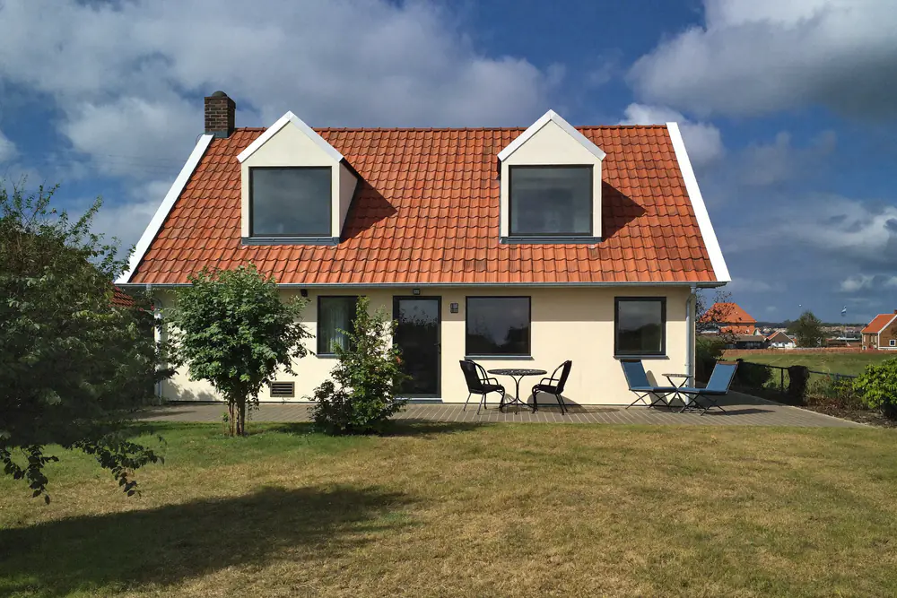 Twee gelijke witte dakkapellen op de achterkant van een vrijstaande woning met tuin